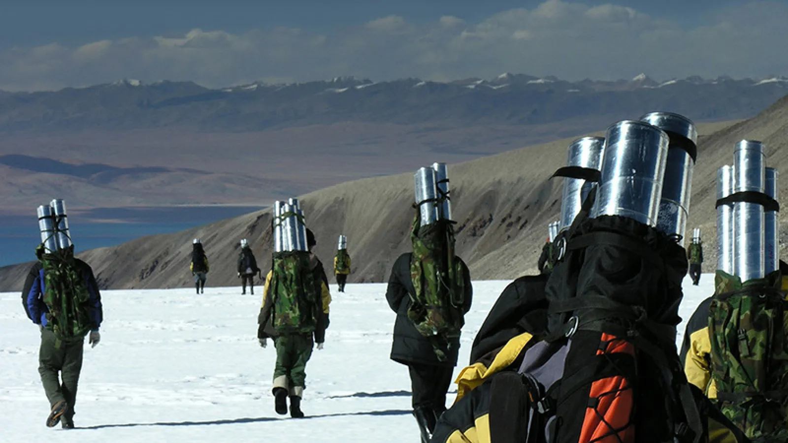 A group of people carry ice cores across the snowy landscape