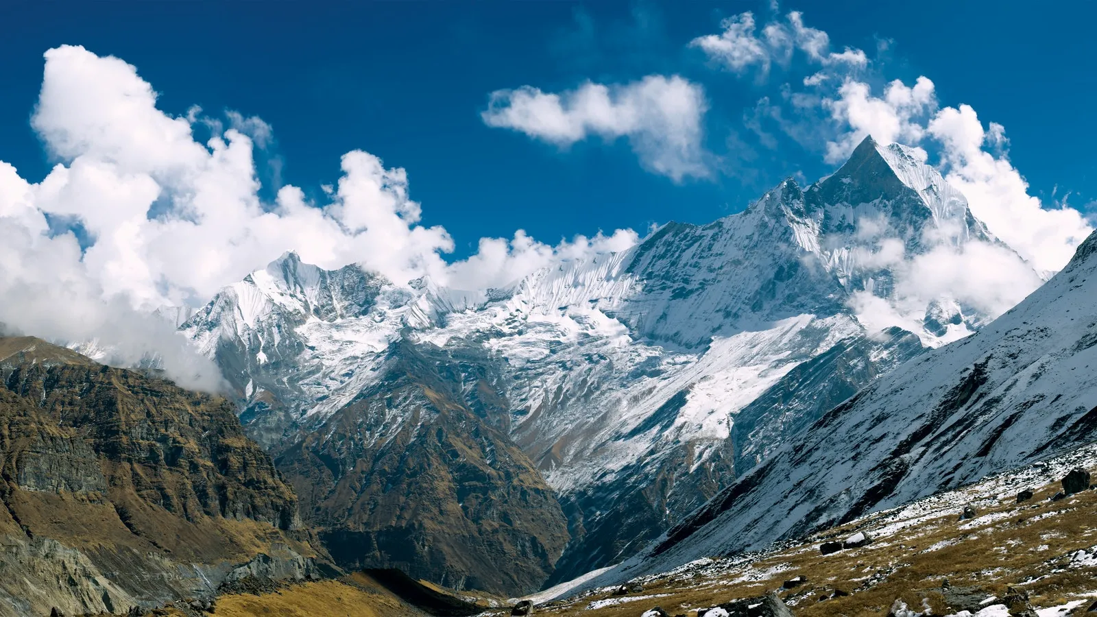 Mountains, some snow covered with blue skies and white clouds 