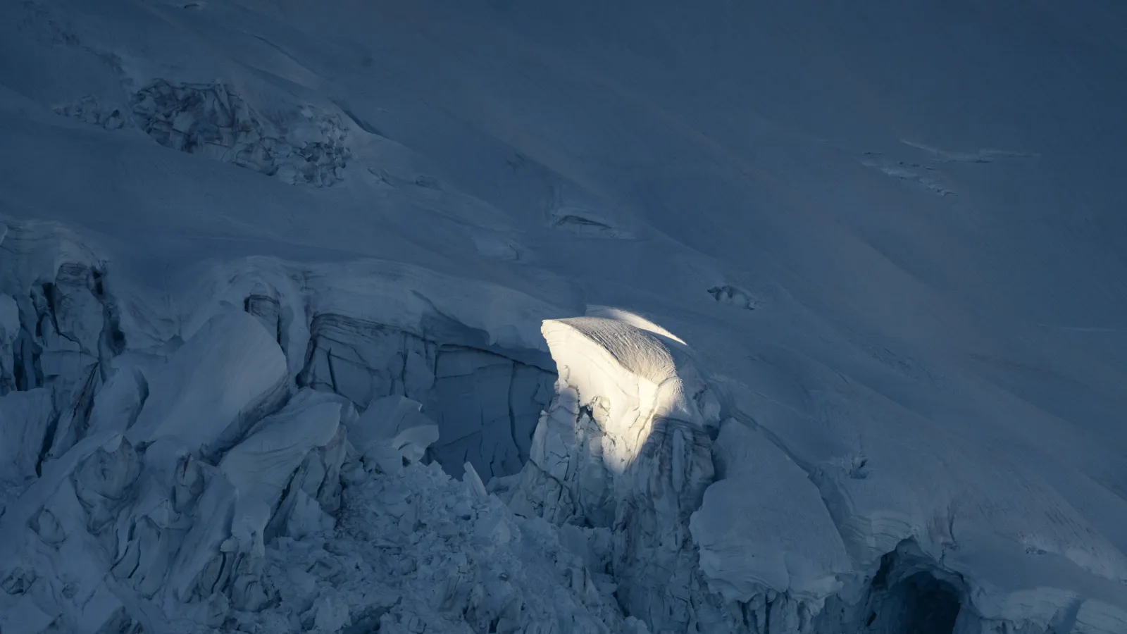 A glacier in the dark with one spot of it lit with a ray of light. 
