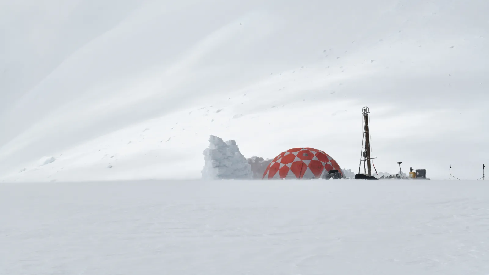 An orange and white tent and drill equipment in a snowy field with white background.