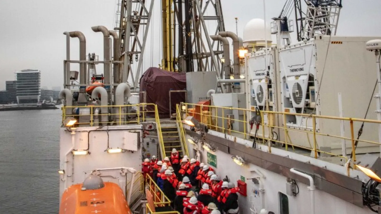 A group of people standing outside on a ship deck during daylight. 