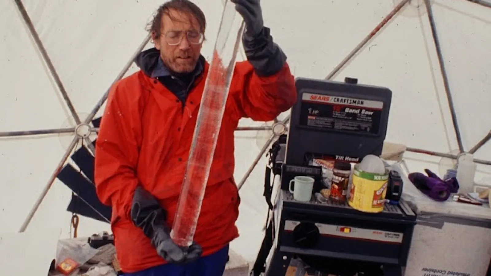 Researcher holding an ice core inside a dome field lab.
