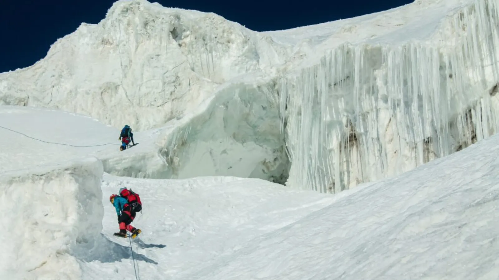 Two polar explorers climbing an icy slope at night