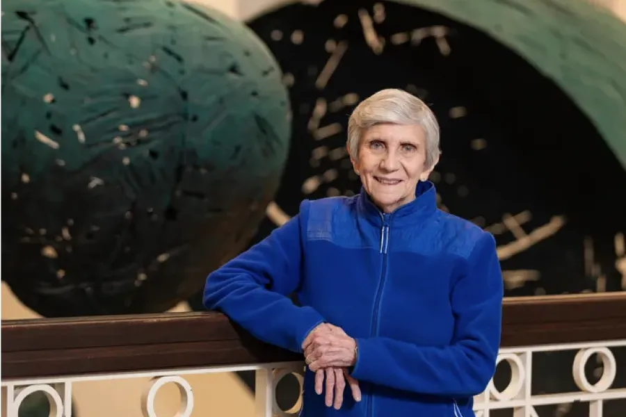 Ellen Mosley-Thompson smiling wearing a bright-blue zip-up jacket leaning against a railing.