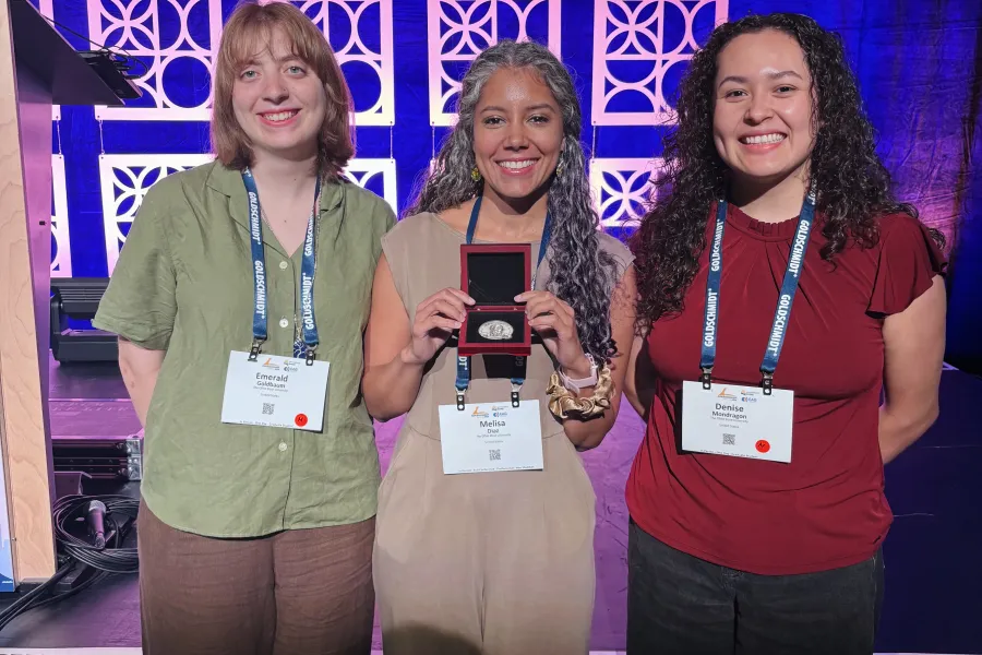 Melisa Diaz standing in the center and smiling holding her F.W. Clarke award