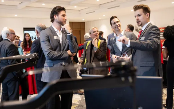 A group of people standing around while one is talking.