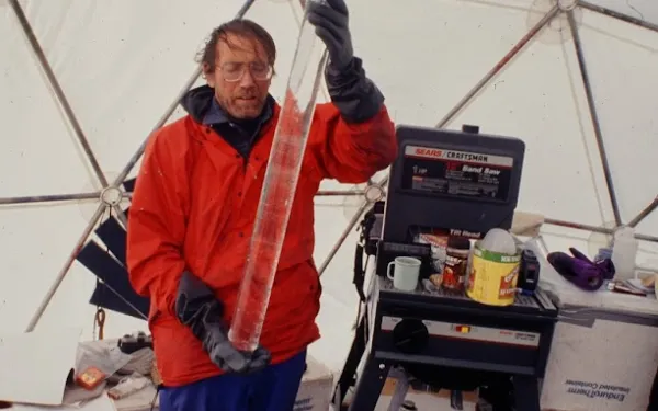 Researcher holding an ice core inside a dome field lab.