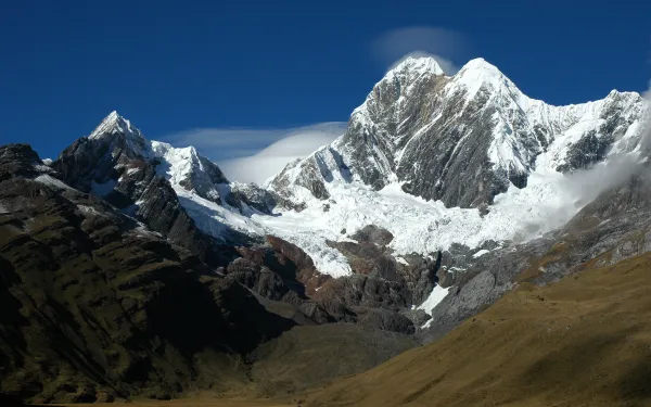 Landscape of mountains with snow covered caps. The sky is a sunny and bright blue