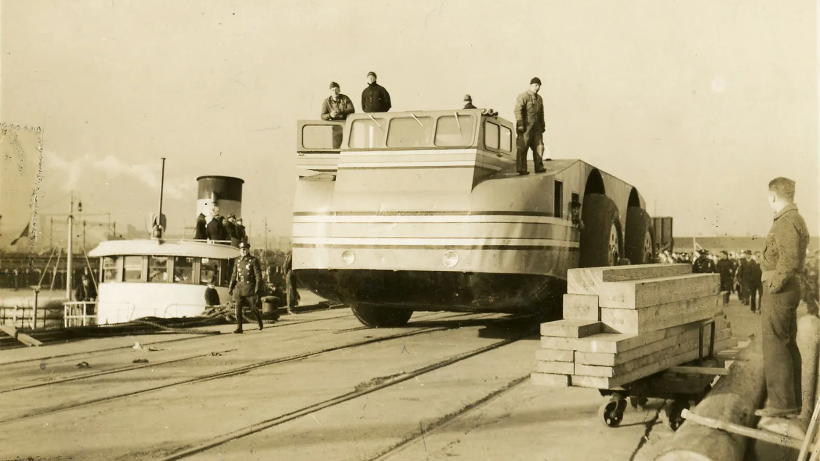 Black and white photo of a snow cruiser being driven through a ship yard
