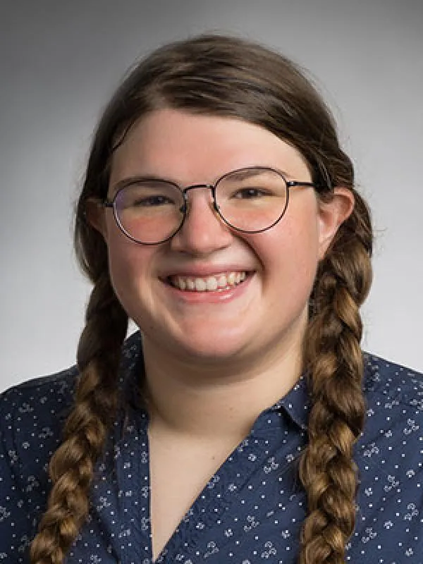 Emily Mazan photo wearing glasses and braided hair smiling with collar shirt