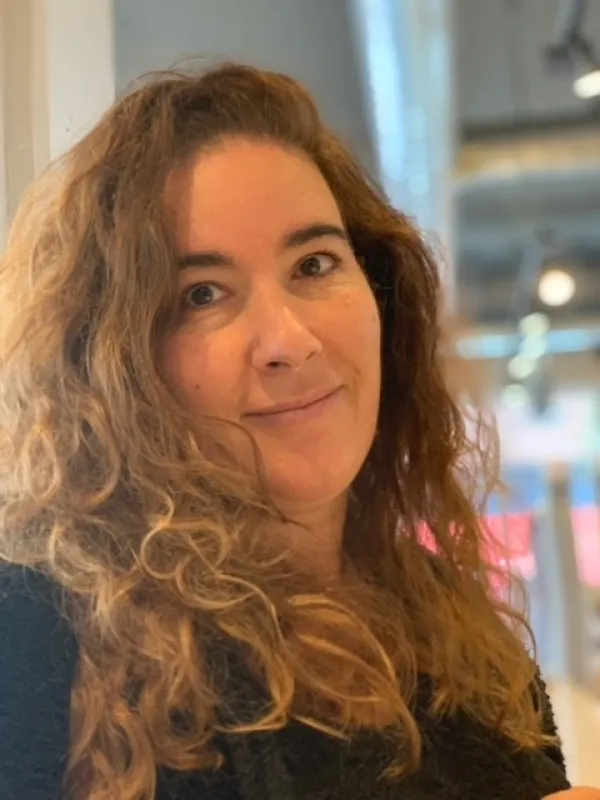 Jennifer Kashani Motlagh head shot smiling at camera with long curly light brown hair h