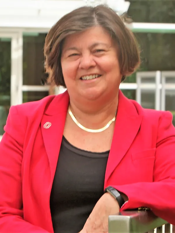 Georgie Shockey smiling, wearing a red blazer with a black shirt and an OSU pin. 