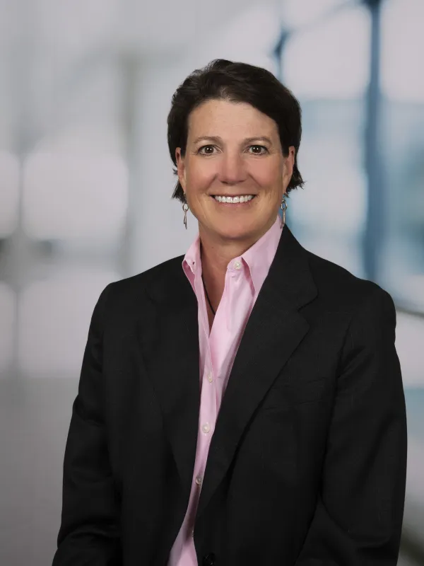 Kristin Watt smiling, wearing a black blazer with a pink dress shirt underneath. 