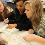 Three students sit around a table and learn about ice cores.